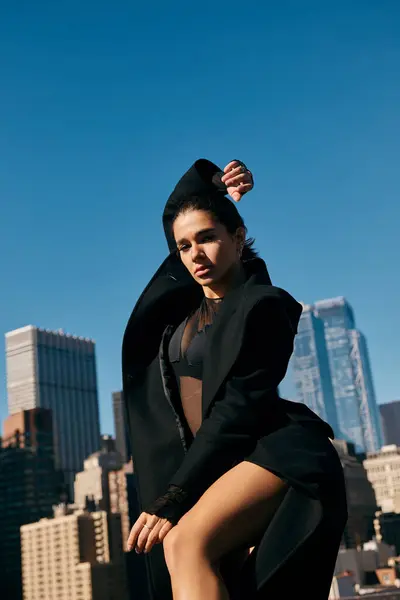 A young woman in a black coat dances on a rooftop in New York City. — Stock Photo