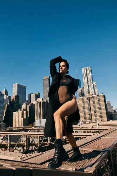 A young woman dances on the Brooklyn Bridge in New York City, wearing a black outfit. — Stock Photo