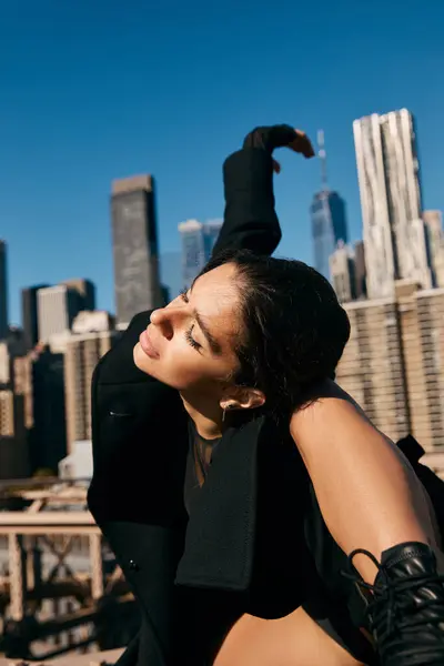 A young woman dances on a rooftop in New York City, her silhouette outlined against the skyline. — Stock Photo