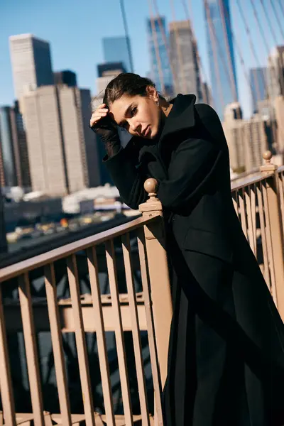 A young woman in a black coat leans against a railing in New York City. — Stock Photo