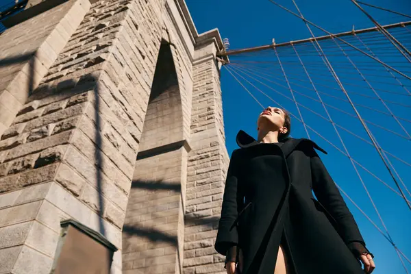 A young woman dances beneath the Brooklyn Bridge on a sunny day. — Stock Photo