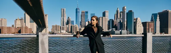 Une jeune femme danse sur un pont à New York, avec l'horizon de la ville en arrière-plan. — Photo de stock