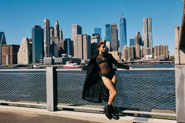 A young woman in a black outfit dances on a pier overlooking the New York City skyline. — Stock Photo
