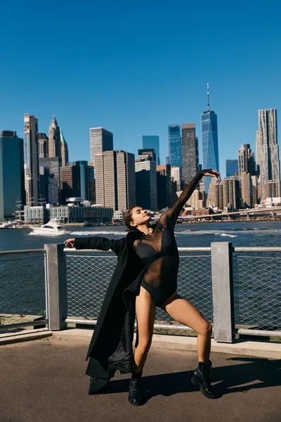 A young woman in a black bodysuit dances on a waterfront walkway in New York City. — Stock Photo