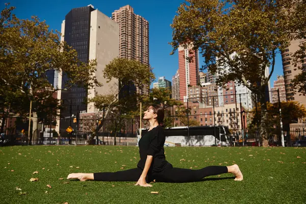 Eine junge Frau macht auf einem grünen Rasen in New York City einen Spagat. — Stockfoto