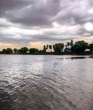Gün batımında bulutlu gökyüzünün altında küçük bir nehrin güzel manzarası.