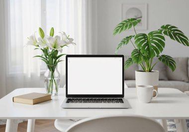 İçinde boş ekranlı bir dizüstü bilgisayar, canavar bitkisi, zambaklar ve kitap olan modern, parlak bir iç mekan..