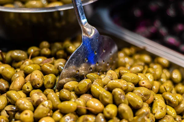pickled olives in a container with spatula