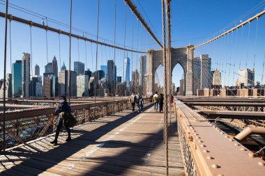 Brooklyn, New York, ABD - 11 Şubat 2023: Brooklyn Köprüsü ve Manhattan, insanların kış günü yürüdüğü Doğu Nehri manzarası.