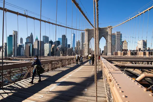 Brooklyn, New York, ABD - 11 Şubat 2023: Brooklyn Köprüsü ve Manhattan, insanların kış günü yürüdüğü Doğu Nehri manzarası.