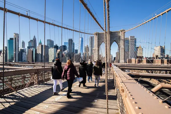 Brooklyn, New York, ABD - 11 Şubat 2023: Brooklyn Köprüsü ve Manhattan, insanların kış günü yürüdüğü Doğu Nehri manzarası.