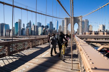 Brooklyn, New York, ABD - 11 Şubat 2023: Brooklyn Köprüsü ve Manhattan, insanların kış günü yürüdüğü Doğu Nehri manzarası.