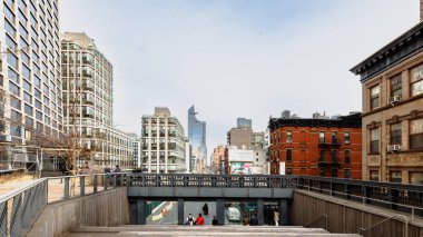 Manhattan, New York, ABD - 16 Şubat 2024: Gri bir kış gününde insanlar tarafından ziyaret edilen tipik binalarıyla Hight Line manzarası
