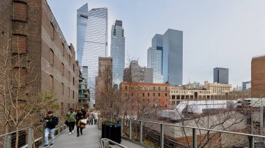 Manhattan, New York, ABD - 16 Şubat 2024: Gri bir kış gününde insanlar tarafından ziyaret edilen tipik binalarıyla Hight Line manzarası