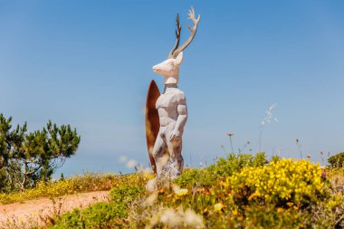 Nazare, Portugal - May 28, 2024: Scultpture Veado by sculptor Adalia Alberto represents the fusion of the local legend, Our Lady of Nazare saving Dom Fuas on a spring day clipart