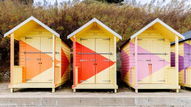 Folkestone, İngiltere - 30 Aralık 2024: Gri bir kış gününde deniz kenarındaki tipik renkli sahil kulübeleri