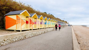 Folkestone, İngiltere - 30 Aralık 2024: Gri bir kış gününde deniz kenarındaki tipik renkli sahil kulübeleri