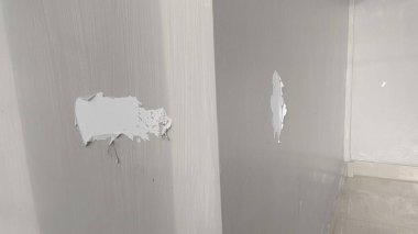 Beyaz bir duvardaki iki deliğin yakın çekim görüntüsü.