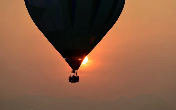Arka planda günbatımı olan bir balon silueti