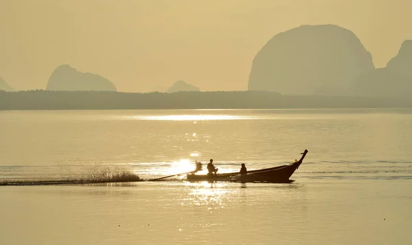 stock image A sailing fishing boat on gold sea surface in a morning