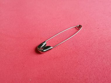 Pembe arka planda metal güvenlik iğnesi, yakın plan.