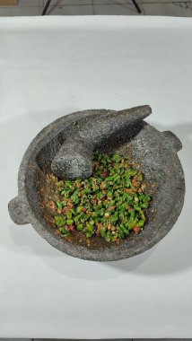 Geleneksel Sundan mutfağına yakın çekim, baharatlı acı biber soslu taze uzun fasulye. Baharat öğütmek için geleneksel taş havan ve tokmakla servis edilir..