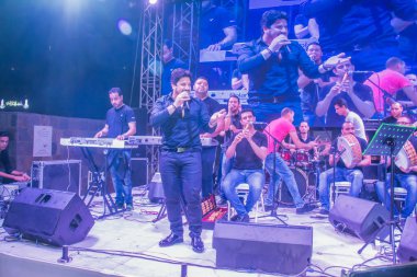 Ramazan çadırı müzikal gösterisi. Şarkıcı Moustafa Hagag ve müzik grubu sahnede. Fotoğraf, yüzeysel alan derinliğiyle seçici bir odak noktasıdır. 22 Mayıs 2018 'de Kahire Mısır' da çekildi.