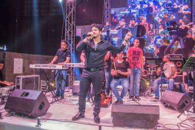 Ramazan çadırı müzikal gösterisi. Şarkıcı Moustafa Hagag ve müzik grubu sahnede. Fotoğraf, yüzeysel alan derinliğiyle seçici bir odak noktasıdır. 22 Mayıs 2018 'de Kahire Mısır' da çekildi.