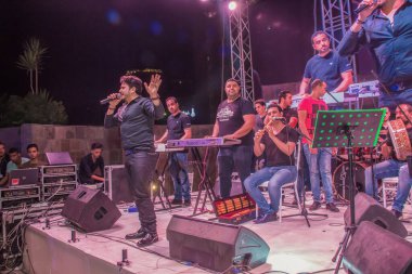 Ramazan çadırı müzikal gösterisi. Şarkıcı Moustafa Hagag ve müzik grubu sahnede. Fotoğraf, yüzeysel alan derinliğiyle seçici bir odak noktasıdır. 22 Mayıs 2018 'de Kahire Mısır' da çekildi.
