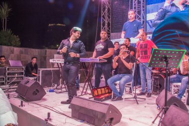 Ramazan çadırı müzikal gösterisi. Şarkıcı Moustafa Hagag ve müzik grubu sahnede. Fotoğraf, yüzeysel alan derinliğiyle seçici bir odak noktasıdır. 22 Mayıs 2018 'de Kahire Mısır' da çekildi.