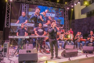 Ramazan çadırı müzikal gösterisi. Şarkıcı Moustafa Hagag ve müzik grubu sahnede. Fotoğraf, yüzeysel alan derinliğiyle seçici bir odak noktasıdır. 22 Mayıs 2018 'de Kahire Mısır' da çekildi.