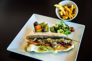 Yemek Fotoğrafları, biftekli sandviç, sebzeli, salatalı ve pomfretli fotoğraf, sığ alan derinliğinde seçici bir odak noktasıdır. Kahire 'deki Sheraton Oteli' nde çekildi.