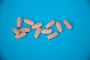 Mavi arka plana izole edilmiş pembe ilaç hapları, sağlık ilaçları, ilaç takviyeleri, tıbbi kapsüller, çoklu vitaminler, kimya, seçici odak, sığ alan derinliği, Kahire Mısır
