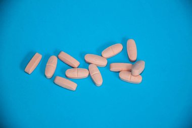 Mavi arka plana izole edilmiş pembe ilaç hapları, sağlık ilaçları, ilaç takviyeleri, tıbbi kapsüller, çoklu vitaminler, kimya, seçici odak, sığ alan derinliği, Kahire Mısır