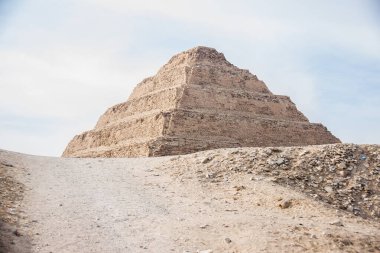 Arkeoloji fotoğrafı, Saqqara tarihte bilinen en eski taş bina kompleksini, Üçüncü Hanedan döneminde inşa edilen Djoser Piramidini, seçici odak ve sığ alan derinliğini içeriyor. Kahire Mısır