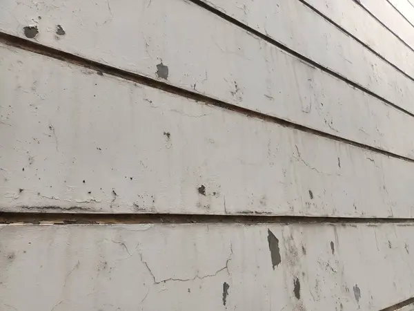 Duvarlar beyaza boyanmış ama boya soyulmaya başlamış ve çatlamış gibi görünüyor.