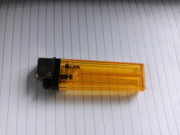 Yaprak kağıdının üzerine yerleştirilmiş turuncu bir gaz çakmağı.