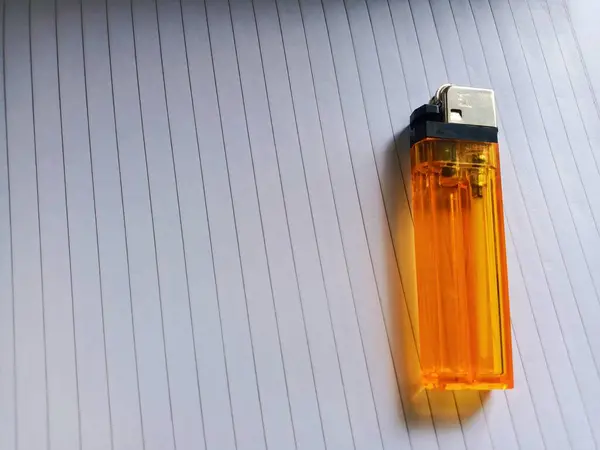 Yaprak kağıdının üzerine yerleştirilmiş turuncu bir gaz çakmağı.