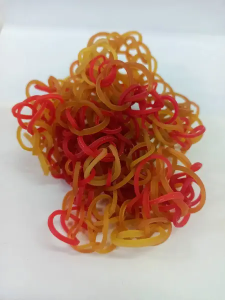 Kauçuk bantlar iki renk kombinasyonu ile kırmızı ve sarı birbirine dolanmış ve beyaz arka planda istiflenmiş..