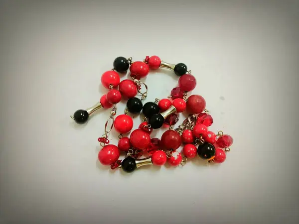 Beyaz arkaplanı olan kırmızı bir marjan taşı kolye.