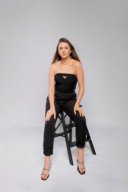 Üzerinde gri arka planda oturan genç bir modelin portresi.,