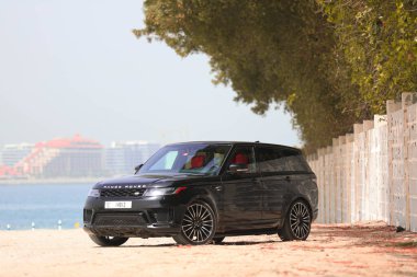 black Luxury Full Option Range Rover Velar Parked showing beautiful Dubai Skyline in background clipart