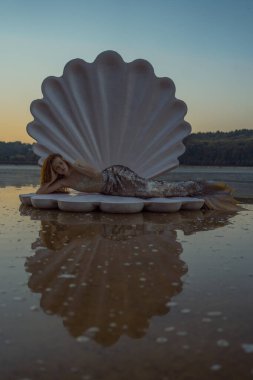 Devasa deniz kabuğu olan güzel kızıl saçlı kadın.