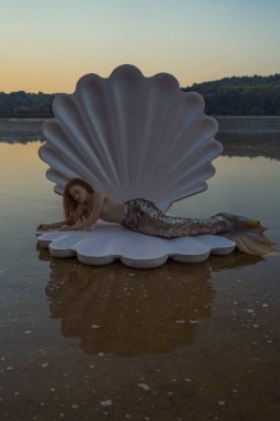 Devasa deniz kabuğu olan güzel kızıl saçlı kadın.