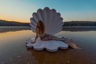 Devasa deniz kabuğu olan güzel kızıl saçlı kadın.