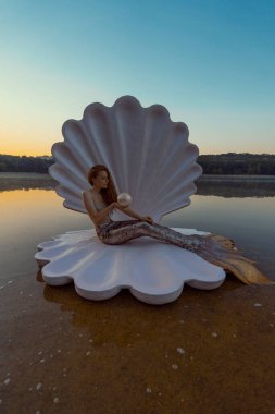 Devasa deniz kabuğu olan güzel kızıl saçlı kadın.