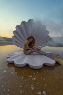 Devasa deniz kabuğu olan güzel kızıl saçlı kadın.