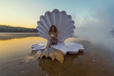 Devasa deniz kabuğu olan güzel kızıl saçlı kadın.