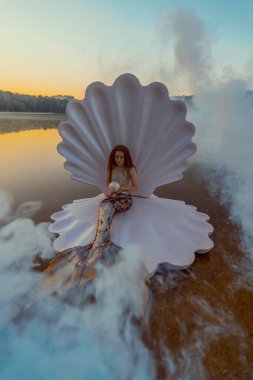 Devasa deniz kabuğu olan güzel kızıl saçlı kadın.