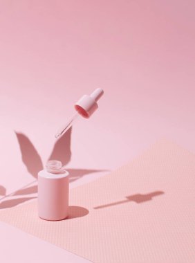 Pastel pembe arka planda cam damlası şişesi. Monokrom rengi. En az sağlıklı konsept.